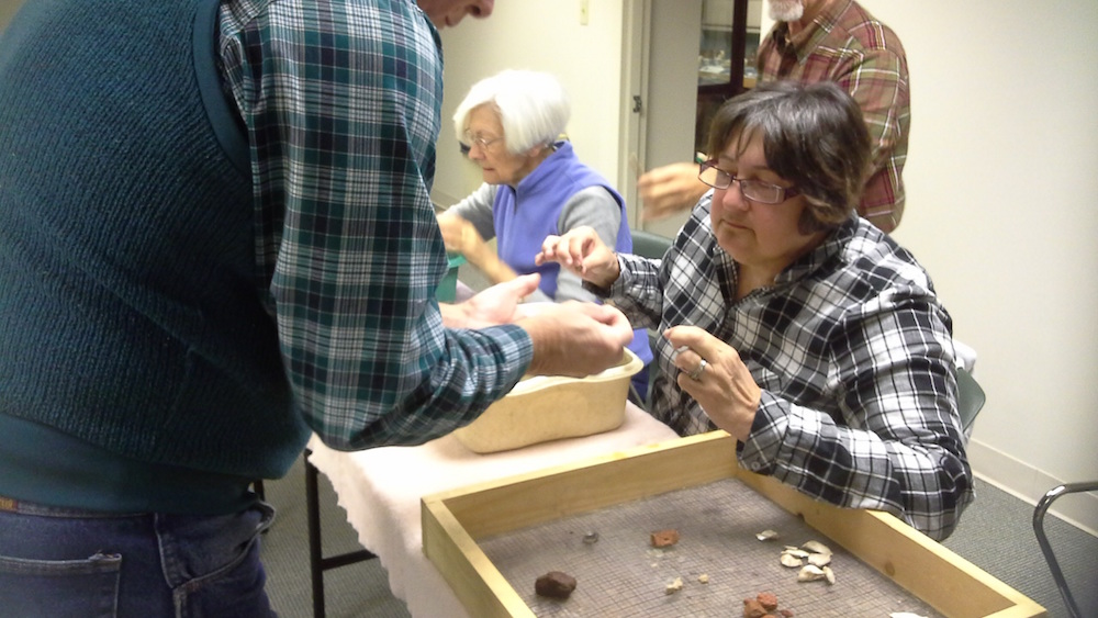 Volunteer Deb Woodward examines an artifact from York County’s New Quarter Park during a recent “Wash and Talk” event. (Courtesy York County Parks, Recreation and Tourism)