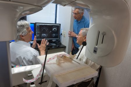 Martin D. Levin (left), Doug Owsley (right) and Barry Pass (background), a professor of oral diagnostics at Howard University, examine a 3D scan of the fort boy’s mandible (mounted in the foreground) in 2014. (Photo by Bruce Dale. Courtesy of Martin D. Levin)