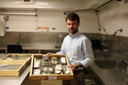 Assistant Curator Hayden Bassett holds a tray of artifacts removed from the floor of the church. (Andrew Harris/WYDaily)