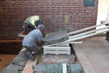 Jonathan Appel (gray shirt) and the Preservation Virginia team used wooden levels and a wooden ramp to move the Knight's Tomb from its spot on the church floor to a place where conservation work can be done. (Courtesy Hayden Bassett)