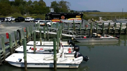 Vessels (including VIMS landing craft R/V Peregrination) loaded with communication gear prepare to head out to Parramore Island. The Suffolk Fire Department’s communications support bus facilitates communication among responders using different frequencies and equipment. (Sean Fate/VIMS ESL/Southside Daily)