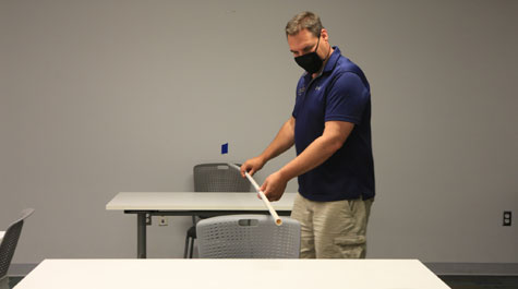 Timothy Russell, William & Mary's university space manager, measures the space between seated students. (WYDaily/Stephen Salpukas, W&M News)